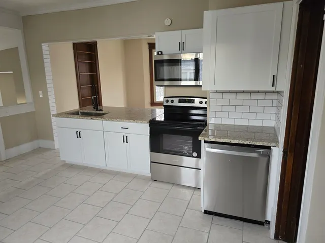 a kitchen with white cabinets and appliances