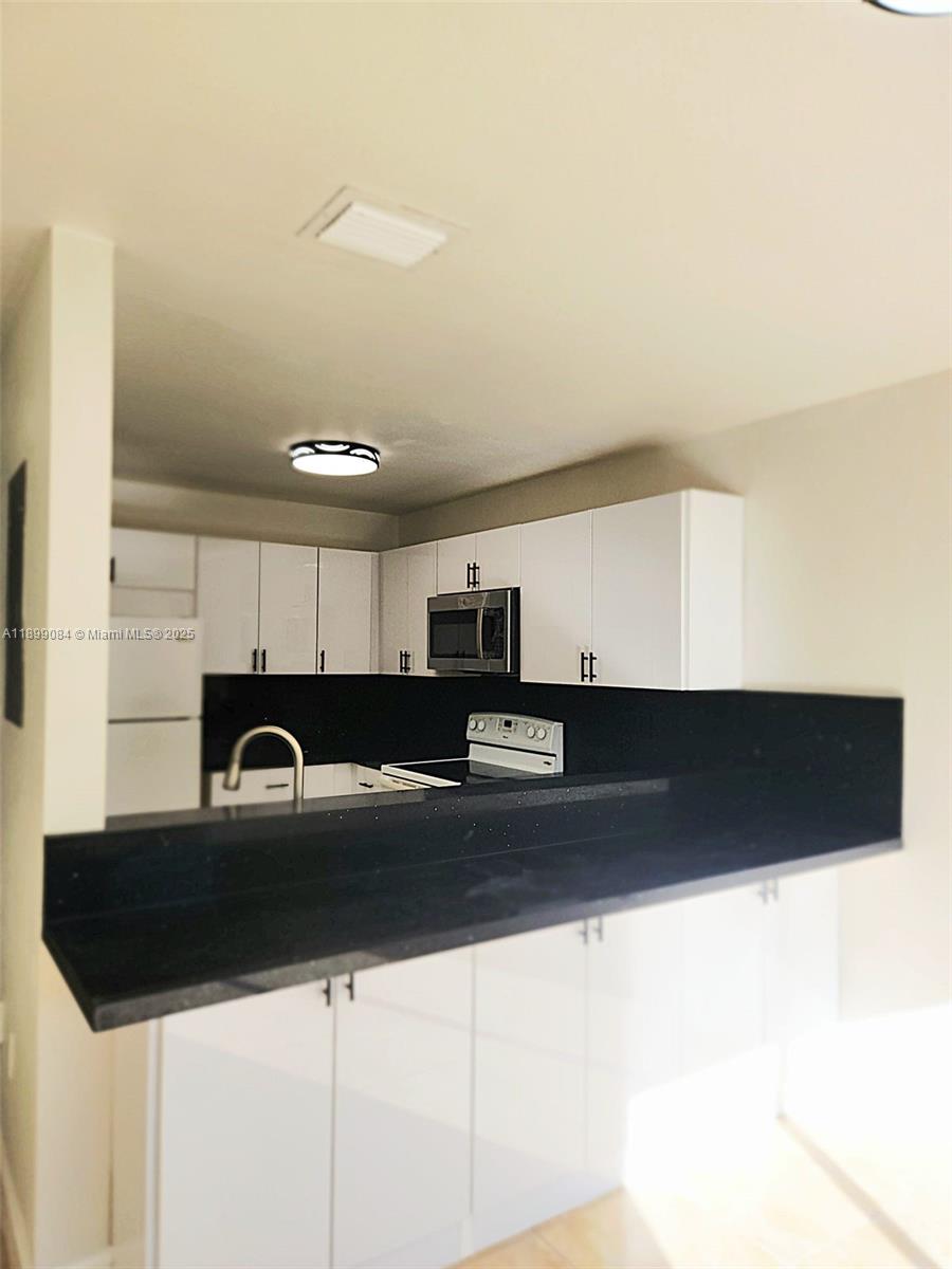 18861 Northwest 86th Court, Unit 3903 Hialeah, FL 33015 - Photo 6 of 14 a kitchen with stainless steel appliances a sink a stove a microwave a sink and cabinets