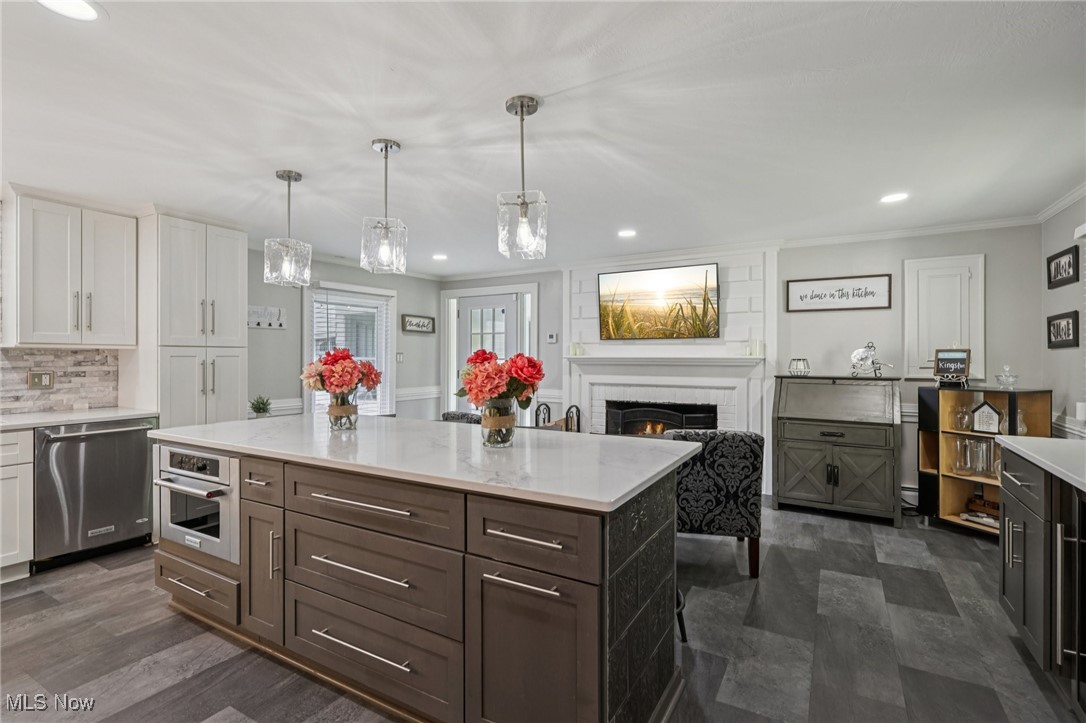 128 Overwood Road Akron, OH 44313 - Photo 13 of 40 Kitchen featuring appliances with stainless steel finishes, light countertops, white cabinetry, ornamental molding, and a brick fireplace