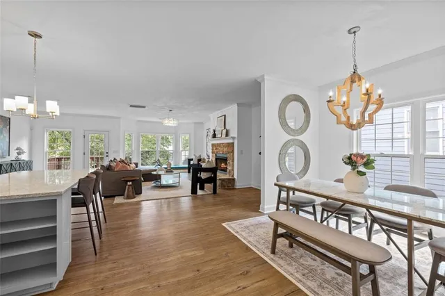 a living room with couches a fireplace and a dining table with wooden floor