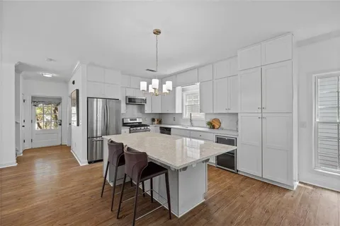 a kitchen with stainless steel appliances a dining table chairs refrigerator and sink