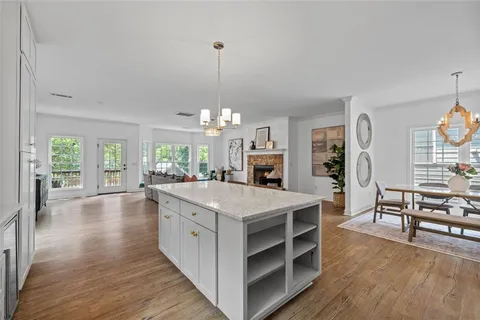 a large kitchen with kitchen island a stove a chimney a sink dishwasher a dining table and chairs with wooden floor