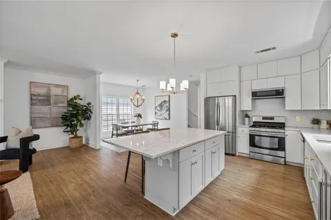 a kitchen with stainless steel appliances a center island wooden floor a stove and a refrigerator