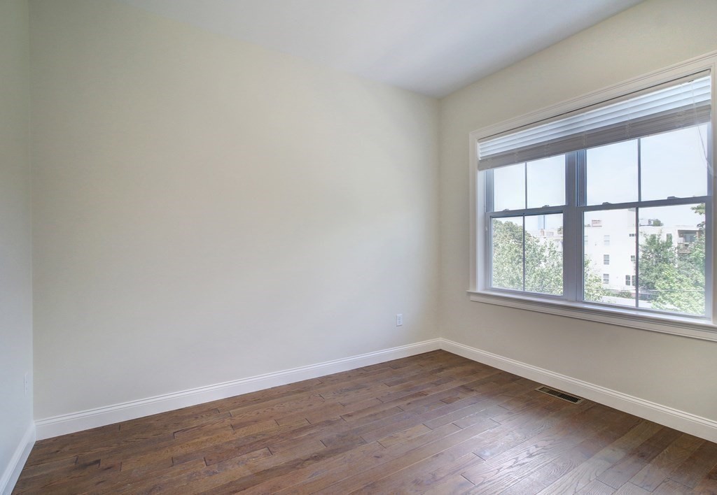 4 Kemp Street, Unit 4 Boston, MA 02127 - Photo 10 of 40 an empty room with wooden floor and windows