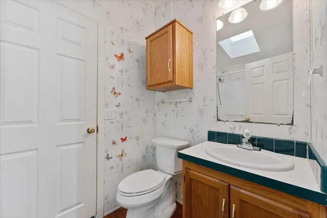 a bathroom with a granite countertop sink toilet and mirror