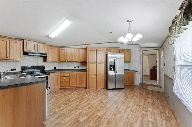a kitchen with stainless steel appliances granite countertop a stove top oven a refrigerator a sink dishwasher with a dining table and chairs with wooden floor