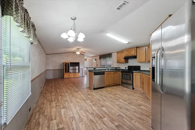 a kitchen with kitchen island granite countertop stainless steel appliances cabinets a sink and a counter top space
