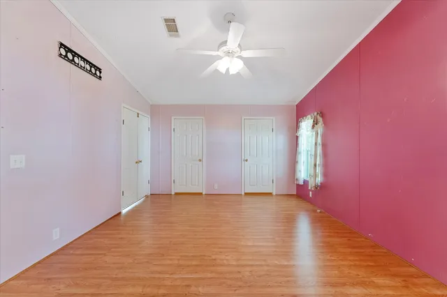 a view of an empty room with window and wooden floor