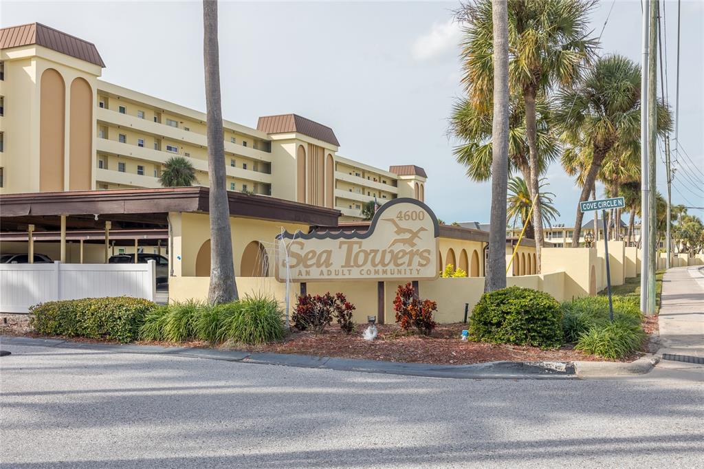 4775 Cove Circle, Unit 1002 Madeira Beach, FL 33708 - Photo 42 of 60 a front view of a building with a garden and plants