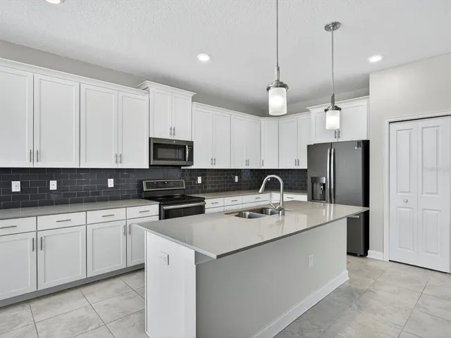 a kitchen with stainless steel appliances granite countertop a sink a stove a refrigerator and cabinets