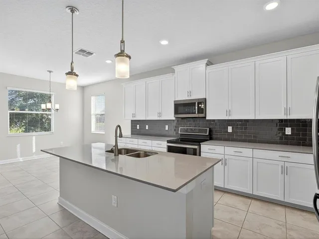 a kitchen with kitchen island granite countertop a sink a counter top space appliances and cabinets