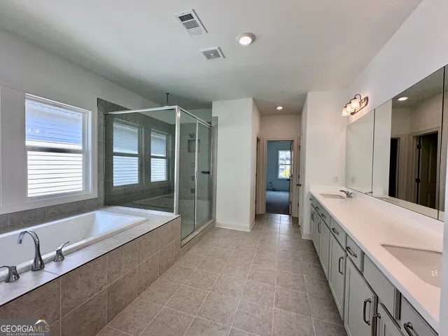 a large en suite bathroom with a tub double sink and mirror