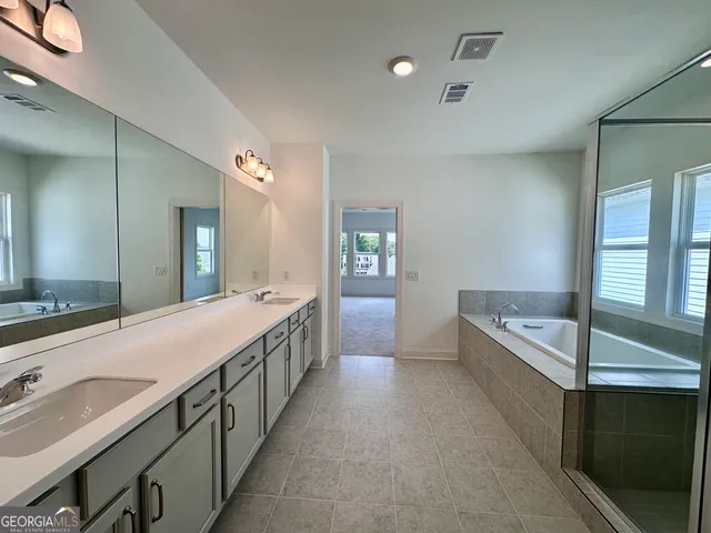 a bathroom with a double vanity sink and mirror with bathtub