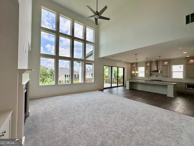 a view of an empty room with a window and kitchen view