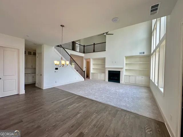 an empty room with wooden floor and a ceiling fan