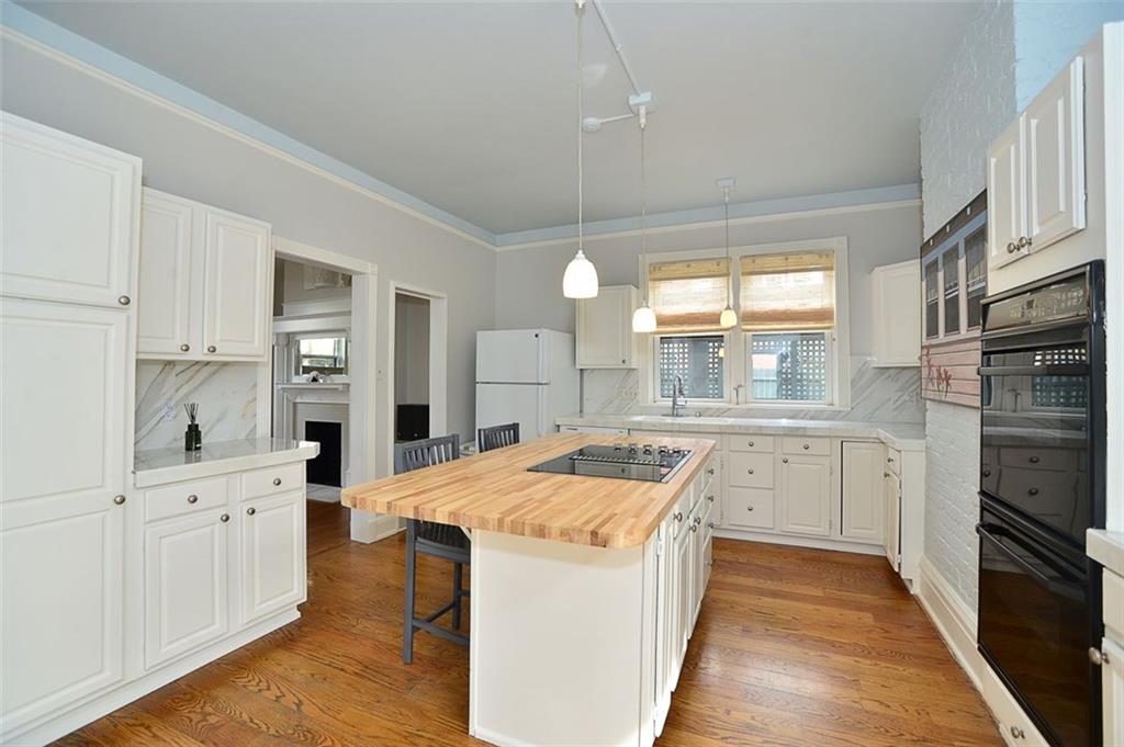 304 Bower Hill Road Pittsburgh, PA 15228 - Photo 8 of 25 Another view of the eat in kitchen with hardwood floors, white cabinetry and center island for seating.