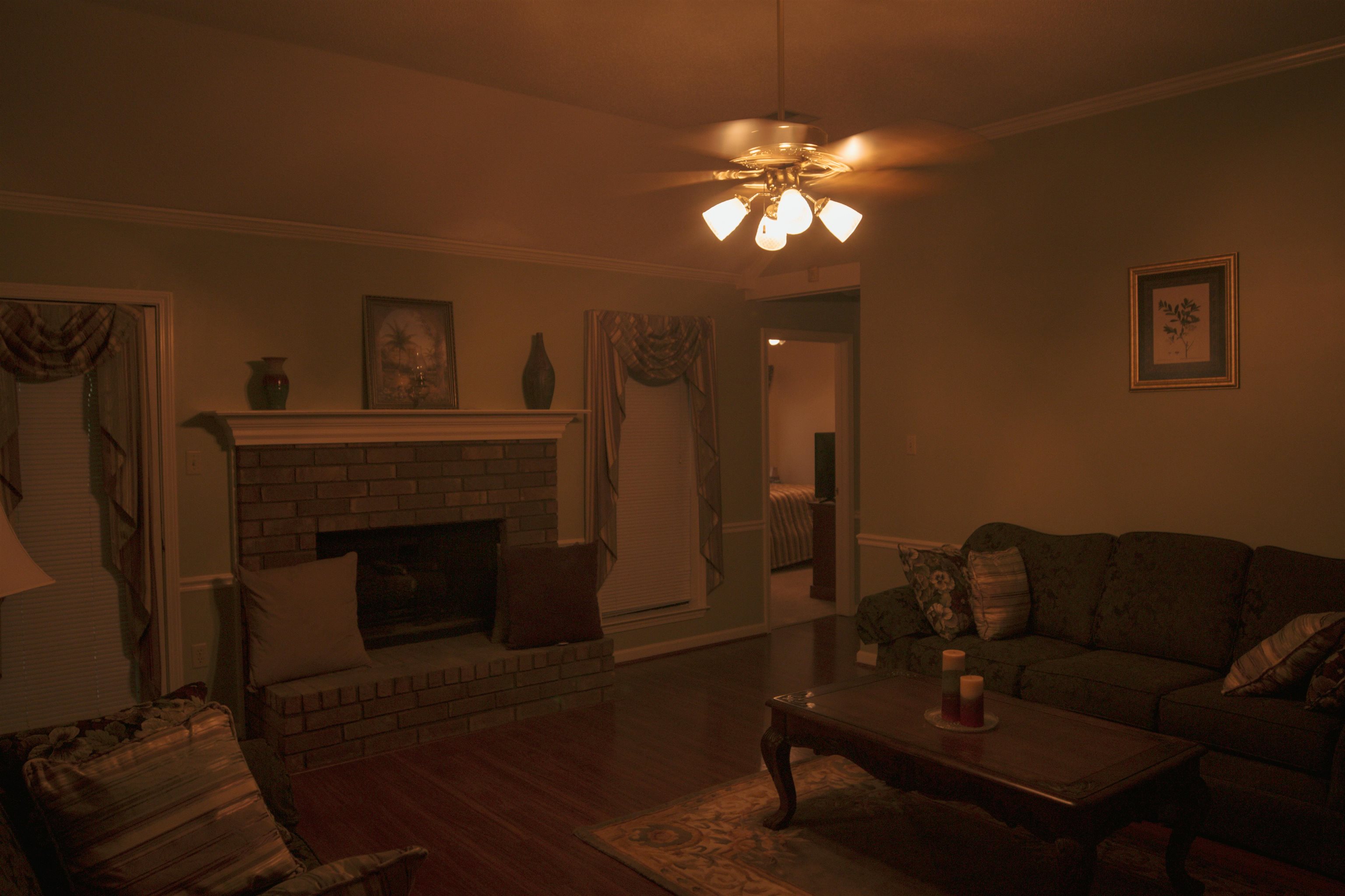 4100 Altruria Road Bartlett, TN 38135 - Photo 3 of 23 Living room with a brick fireplace, ceiling fan, crown molding, and dark wood-type flooring