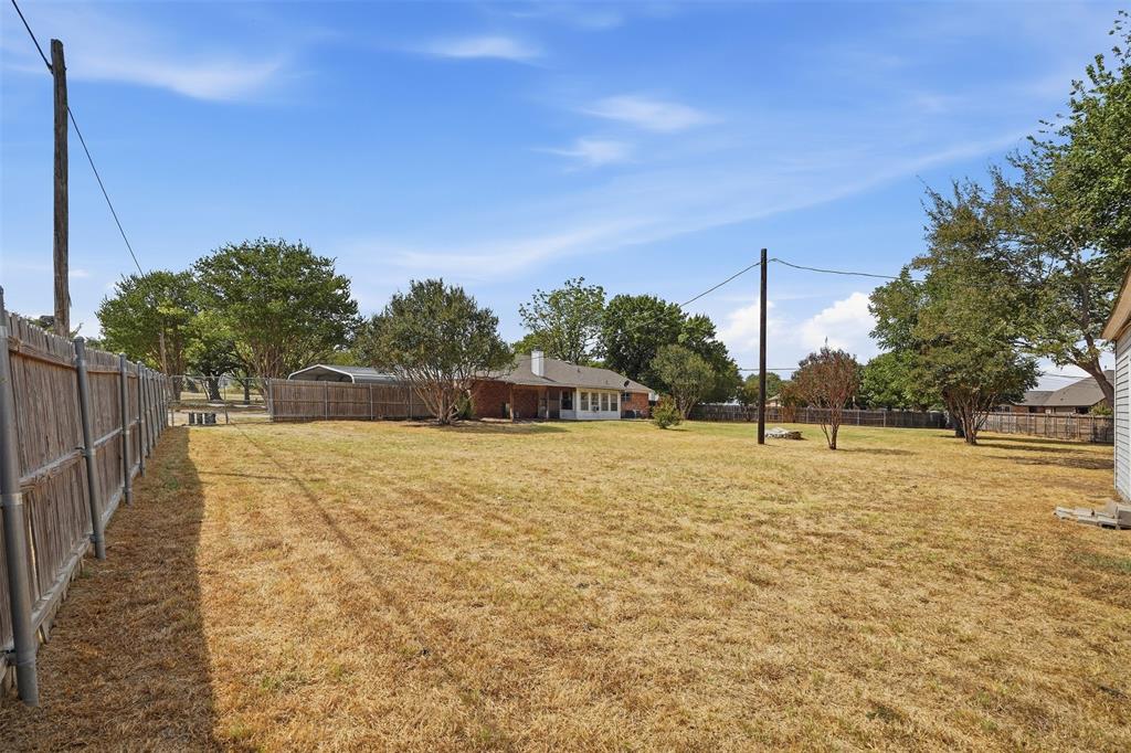 6880 Sandy Beach Road Azle, TX 76020 - Photo 28 of 32 Expansive backyard featuring a wood privacy fence, mature trees, and a detached shed