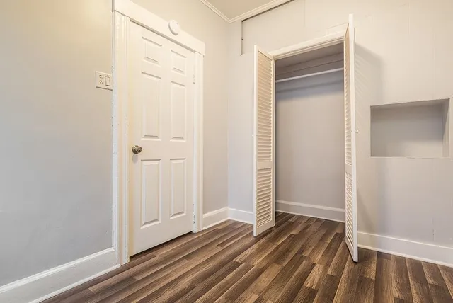 a view of a hallway with wooden floor and closet area
