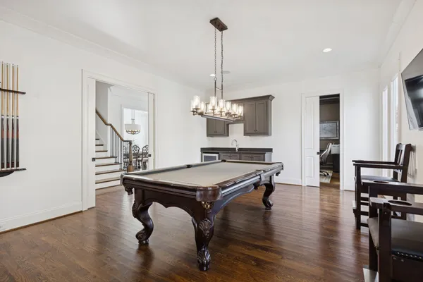 a kitchen with stainless steel appliances granite countertop a sink dishwasher a refrigerator and white cabinets with wooden floor