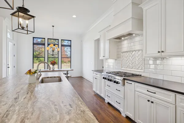 a white bed sitting in a bedroom next to a window and a chandelier