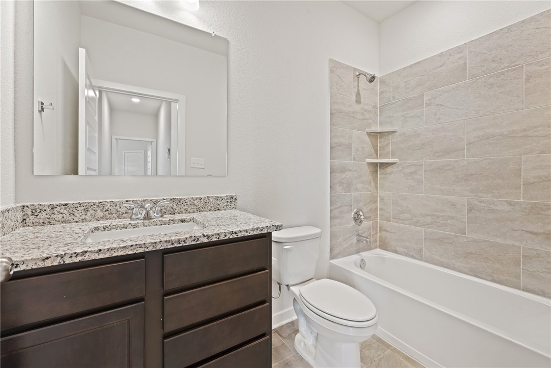 2412 Rooke Road Bryan, TX 77807 - Photo 31 of 35 a bathroom with a granite countertop toilet a sink and a bathtub
