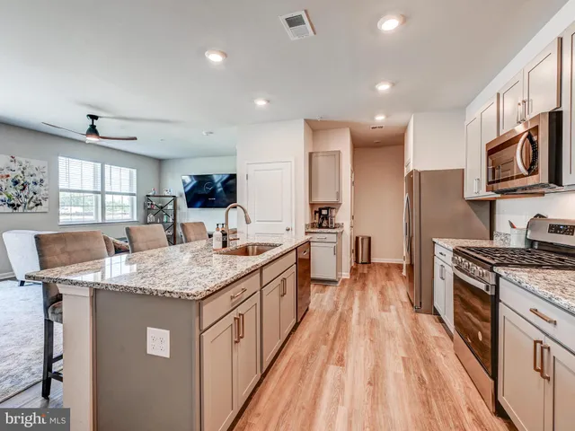 a kitchen with granite countertop a sink a counter top space stainless steel appliances and cabinets