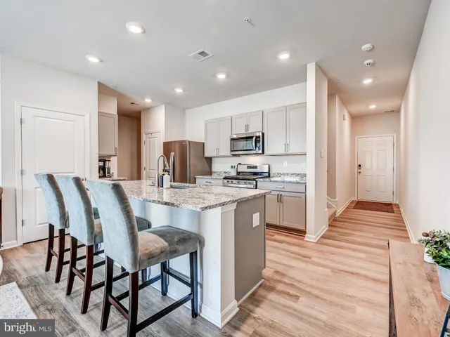 a kitchen with kitchen island granite countertop wooden floors and white cabinets