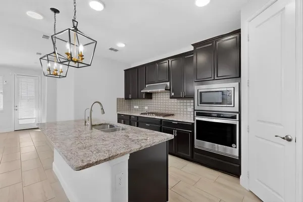 a kitchen with a sink chandelier and living room view