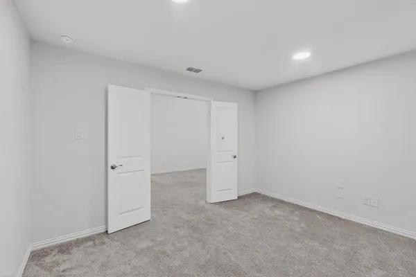 an empty room with chandelier fan and windows