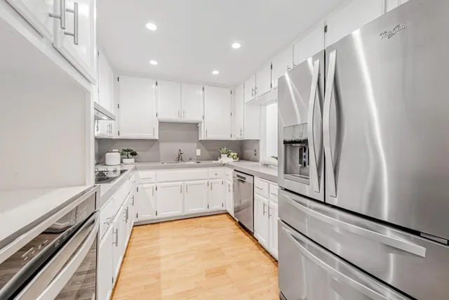 a kitchen with stainless steel appliances granite countertop a sink white cabinets and a granite counter tops