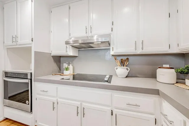 a kitchen with stainless steel appliances white cabinets and a refrigerator