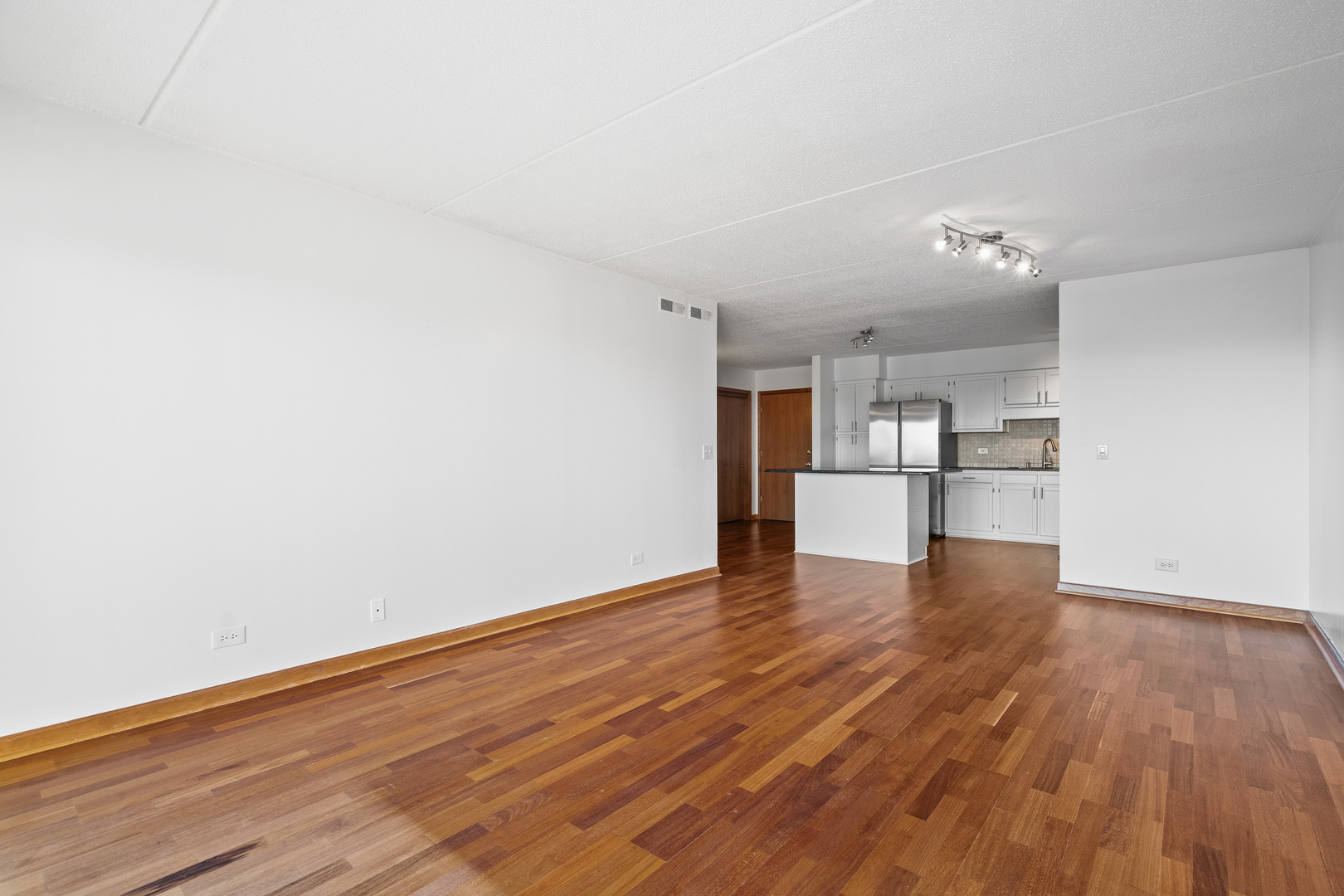 6400 West Berteau Avenue, Unit 405 Chicago, IL 60634 - Photo 9 of 22 a view of empty room with wooden floor and kitchen