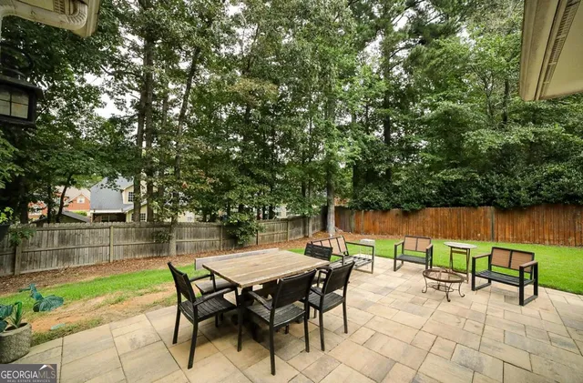 a view of a patio with table and chairs and potted plants with large tree
