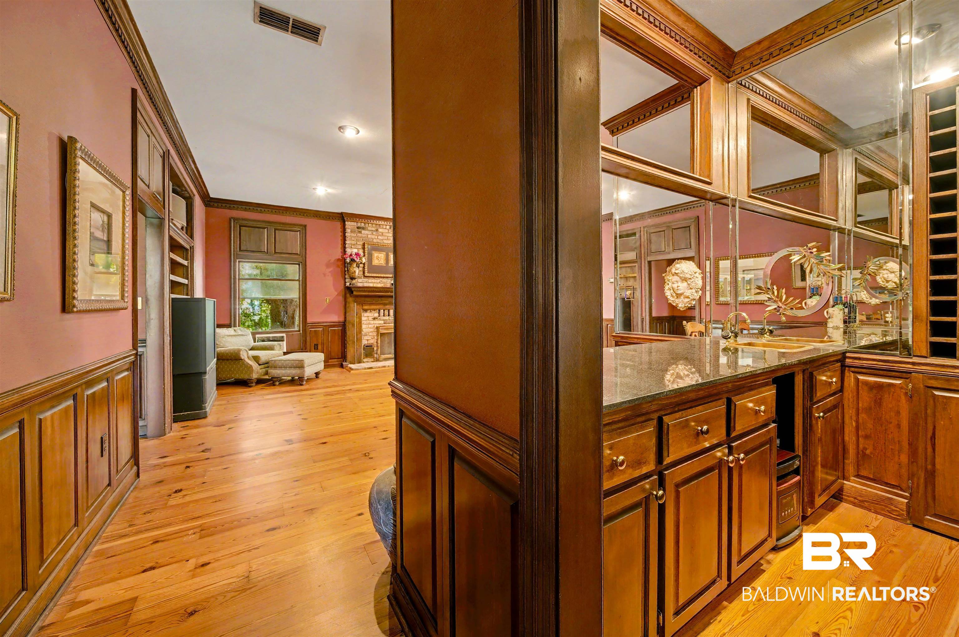 15810 County Road 73 Foley, AL 36535 - Photo 42 of 56 Bar area featuring dark stone counters, ornamental molding, light wood-style floors, wainscoting, and a decorative wall