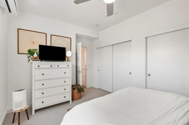 a bedroom with a bed and a flat tv screen on wall