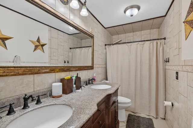 a bathroom with a granite countertop sink a mirror and shower