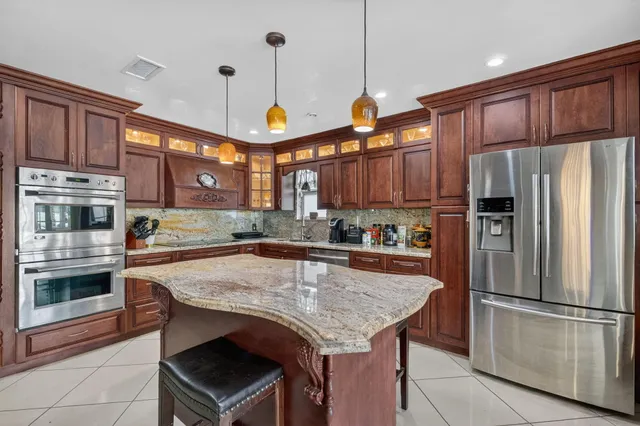 a kitchen with stainless steel appliances granite countertop a refrigerator a stove a sink and a refrigerator