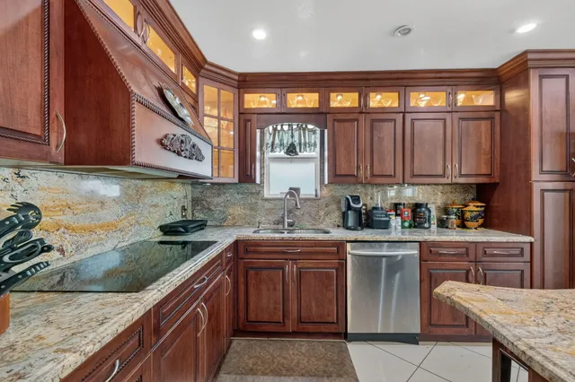 a kitchen with stainless steel appliances granite countertop wooden cabinets a stove top oven a sink and dishwasher