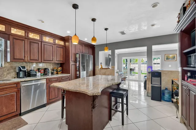 a kitchen with stainless steel appliances granite countertop wooden cabinets a center island and a refrigerator