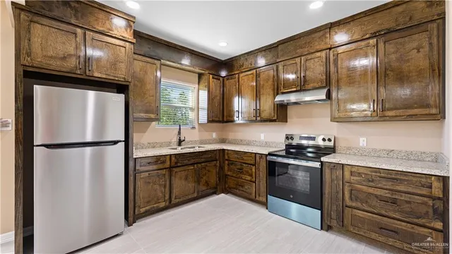 a kitchen with stainless steel appliances granite countertop a refrigerator a sink a stove and cabinets