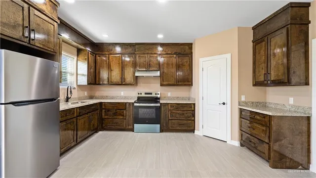 a kitchen with granite countertop a refrigerator stove top oven and sink