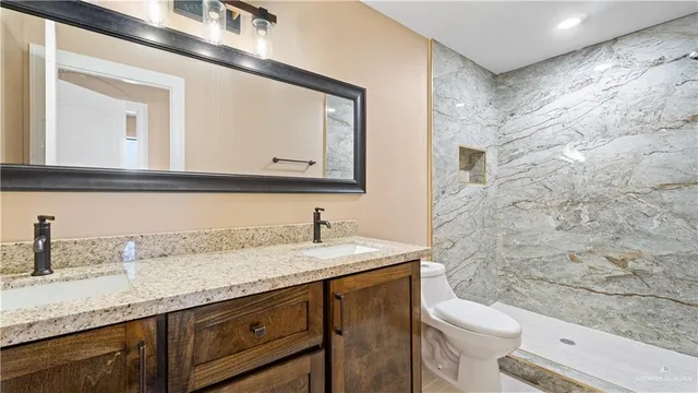 a bathroom with a granite countertop sink vanity mirror and toilet