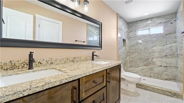 a bathroom with a granite countertop sink a toilet and a mirror