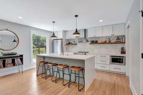 a kitchen with stainless steel appliances granite countertop white cabinets a stove a sink and a wooden floors