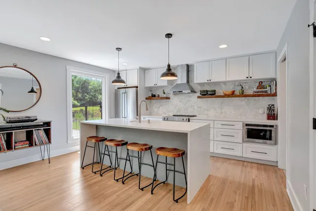 a kitchen with stainless steel appliances granite countertop white cabinets a stove a sink and a wooden floors