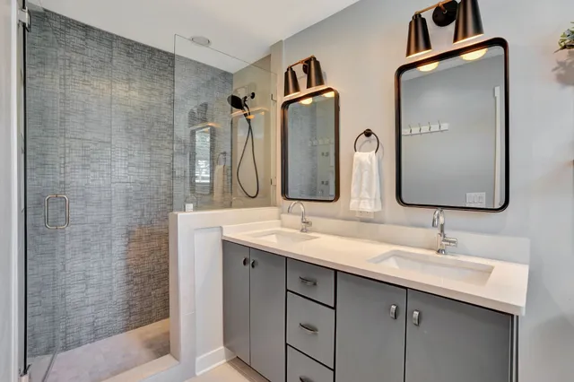 a bathroom with a granite countertop sink a mirror and shower