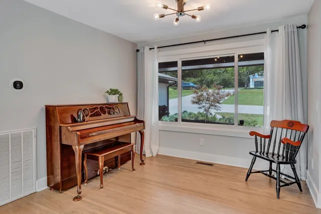 a living room with a piano and a window