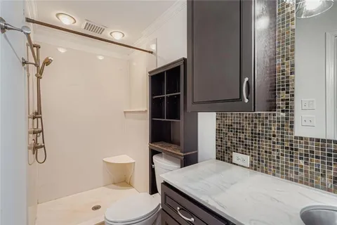 a bathroom with a granite countertop sink a toilet and shower