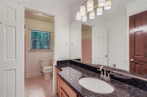 a bathroom with a granite countertop double vanity sink a mirror and a toilet